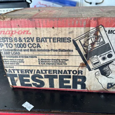 Vintage Snap-on battery and alternator tester in its original cardboard box, showing wear and staining.