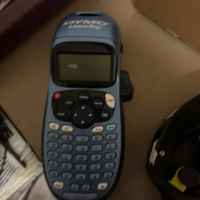 Handheld metallic blue Dymo LetraTag personal label maker with QWERTY keypad and LCD screen.