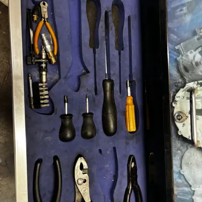 Tool chest drawer featuring custom blue foam organizer inserts filled with assorted hand tools, including pliers, screwdrivers, and...