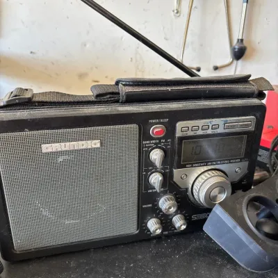 Grundig S350 portable field radio with telescopic antenna, carrying strap, and digital display, showing light surface wear and dust.
