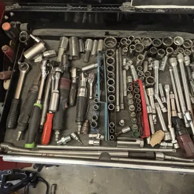 Toolbox drawer filled with an assortment of socket wrenches, ratchet handles, extensions, and individual sockets in various sizes.