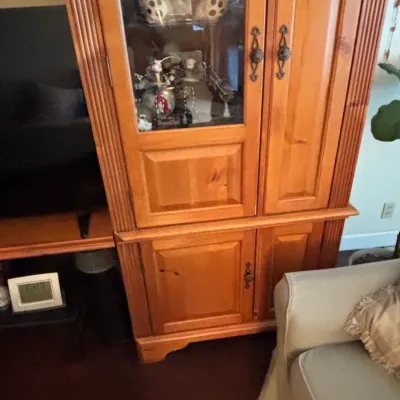 Traditional pine display cabinet with glass upper doors, lower storage cabinets, and ornate bronze hardware.