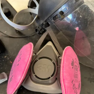 3M half-facepiece reusable respirator with pink P100 particulate filters, shown alongside a clear protective face shield.