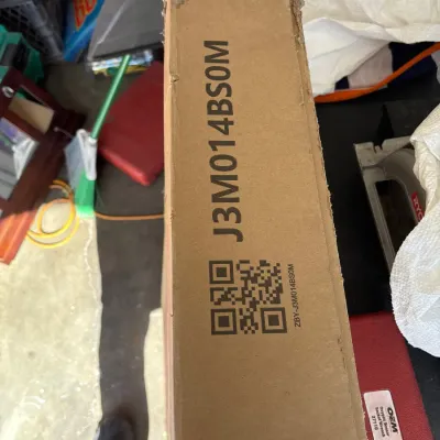 Cardboard shipping box labeled with alphanumeric code J3M014BS0M and a QR code.