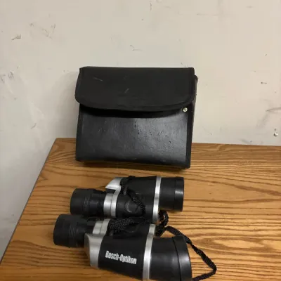 Pair of Bosch-Optikon silver and black binoculars with neck strap, complete with black carrying case.