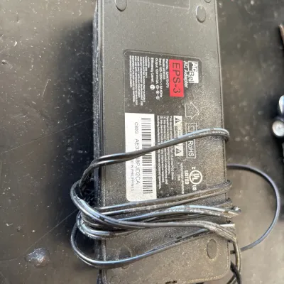AcBel AC adapter power supply brick, EPS-3 model ADE033, showing minor surface wear and wrapped cord.