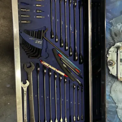 Toolbox drawer filled with an organized set of combination wrenches, sockets, hex keys, and marking utensils stored in custom blue foam...