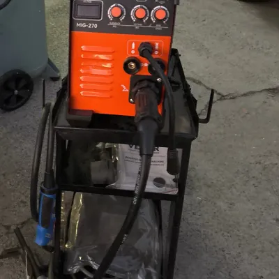 VEVOR MIG-270 multi-process inverter welding machine on a black metal rolling cart with attached cables and accessories.