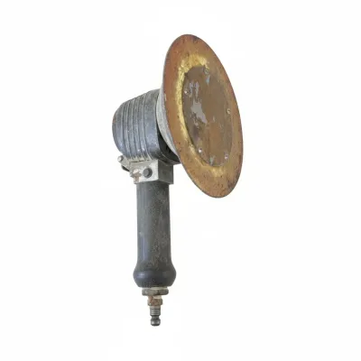 Vintage pneumatic disc sander with a heavy-duty metal housing, black rubber handle grip, and surface rust on the sanding pad holder.