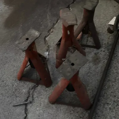 Set of four vintage orange automotive jack stands showing heavy surface wear and patina.