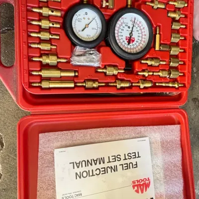 Mac Tools fuel injection test set housed in a red molded plastic carrying case with original instruction manual.