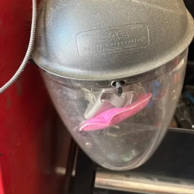 SAS Safety Corporation full face shield, featuring a clear plastic visor and a dark gray brow guard. It shows minor surface wear and dust...