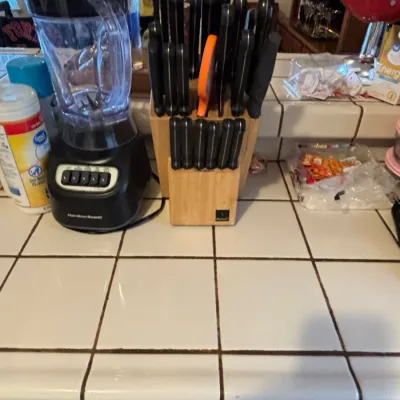 Hamilton Beach blender alongside large wooden knife blocks filled with cutlery on a tiled kitchen counter.