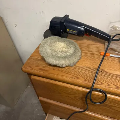 Wen 7-inch sander/polisher tool resting on an oak wooden dresser next to a fleece buffing bonnet.