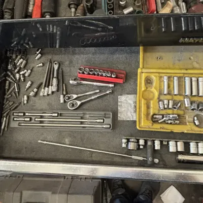 Open Matco tool chest drawer filled with various sockets, ratchets, extensions, and drive bits in organized trays.
