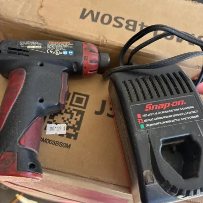 Snap-on 7.2V cordless screwdriver tool with matching battery charger dock, showing signs of heavy workshop use.
