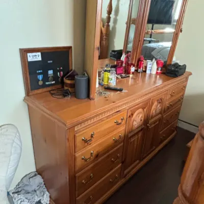 Large wooden dresser featuring brass bail handles, carved center cabinet doors, and a tri-fold attached mirror.