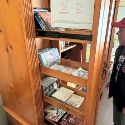 Large pine entertainment armoire featuring pull-out media shelves filled with CDs, DVDs, and electronics.