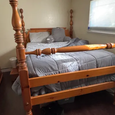 Traditional pine four-poster bed frame featuring pineapple finials, turned posts, and a matching footboard.