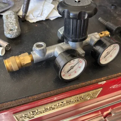 Pneumatic air pressure regulator manifold with dual analog pressure gauges and brass quick-connect fitting resting on a red Matco tool...