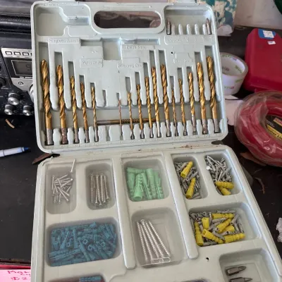 Drill bit and wall anchor set in a plastic molded carry case, featuring an assortment of titanium-coated drill bits, screws, and colorful...