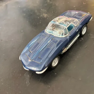 Vintage dark blue Chevrolet Corvette die-cast model car with a clear bubble top roof and wire wheels.
