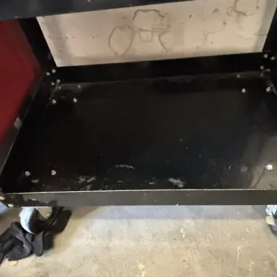 Black metal rolling utility cart with a lower tray shelf and heavy-duty casters.