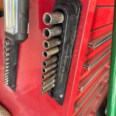 Magnetic socket holder with a set of deep-well sockets attached to the side of a red tool chest.