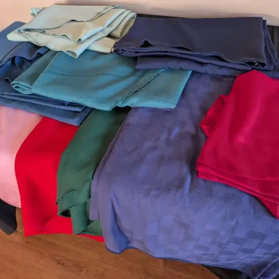 Colorful Assortment of Folded Tablecloths and Fabric Lengths in Jewel Tones