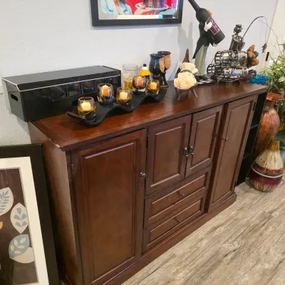 Sale Photo Thumbnail #6: Dark cherry wood buffet credenza with multi-compartment storage cabinets and center drawers, displaying decorative candle holders, wine accessories, and bar decor.