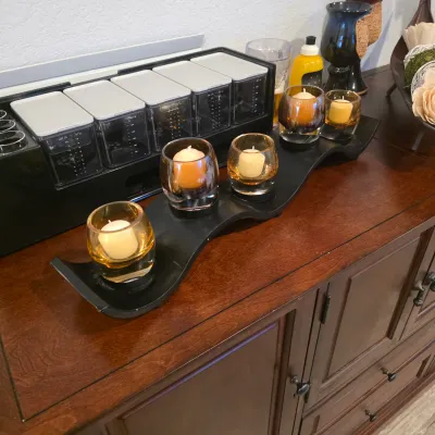Sale Photo Thumbnail #9: A modern wavy black candle holder tray with amber glass votive cups, displayed alongside kitchen bar organizers on a dark wood cabinet.