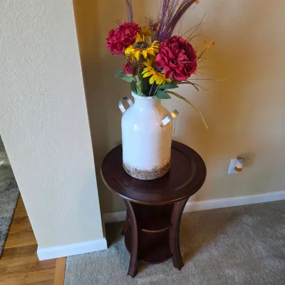 Sale Photo Thumbnail #67: Faux floral arrangement in a distressed white metal milk-can vase, displayed on a dark wood round accent table.