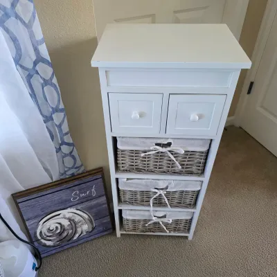 Sale Photo Thumbnail #93: White coastal-style storage cabinet featuring two top drawers and three fabric-lined woven wicker baskets, displayed alongside a framed seashell graphic print.