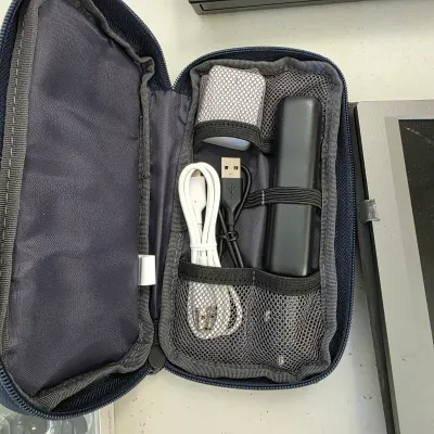 Sale Photo Thumbnail #157: Navy blue travel cable organizer pouch containing assorted USB cords, an adapter, and a portable power bank.