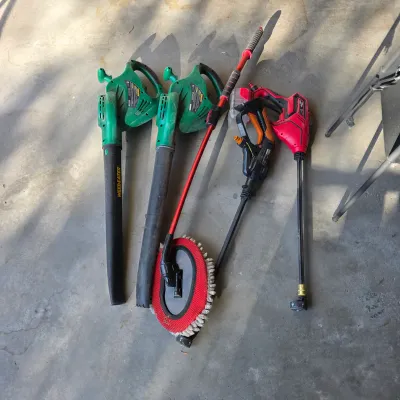 Sale Photo Thumbnail #131: Collection of outdoor lawn care equipment including two green Weed Eater leaf blowers, a pressure washer wand attachment, and a wash brush wand.