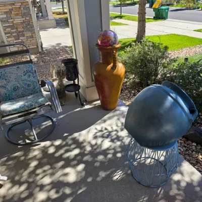 Sale Photo Thumbnail #120: Collection of outdoor patio items including a cushioned swivel chair, decorative large urn with iridescent gazing ball, and garden stands.