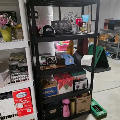 Sale Photo Thumbnail #50: Black plastic four-tier shelving unit holding various household items, decorative signs, glassware, and small storage boxes.