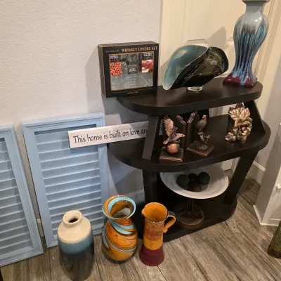 Sale Photo Thumbnail #40: A collection of home decor items, including ceramic and art glass vases, bookends, a three-tier dark wood shelving unit, and light blue wooden shutters.