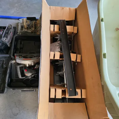 Sale Photo Thumbnail #143: Lawn aerator attachment packed in its original cardboard box, stored alongside power tools including a Craftsman circular saw.