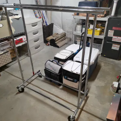Sale Photo Thumbnail #47: Heavy-duty dual-rail chrome rolling clothing rack set on caster wheels, shown with soft and hard coolers stacked beneath.