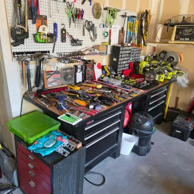 Sale Photo Thumbnail #137: Workshop area filled with various hand tools, power tools, tool chests, and a wall-mounted pegboard organization system.