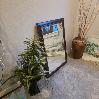 Sale Photo Thumbnail #21: Large dark wood framed floor mirror displayed alongside a tall decorative vase with curly twigs and a potted artificial plant.