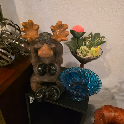 Sale Photo Thumbnail #13: Whimsical resin moose figurine seated next to a blue Moon and Stars pattern glass bowl and artificial flower arrangement.