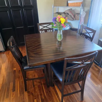 Sale Photo Thumbnail #101: Dark wood counter-height dining table with four matching chairs featuring X-back details and black cushioned seats.