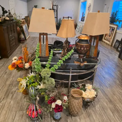 Sale Photo Thumbnail #43: A collection of home decor items featuring table lamps, decorative urns, artificial flower arrangements, and a glass-topped chrome console table.