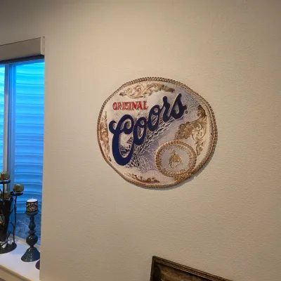 Sale Photo Thumbnail #25: Vintage Original Coors oval belt buckle-style bar sign with Western motif and rope border.