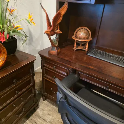 Sale Photo Thumbnail #37: Traditional dark wood executive desk with matching filing cabinet, featuring a resin eagle statue and miniature tabletop globe decor.