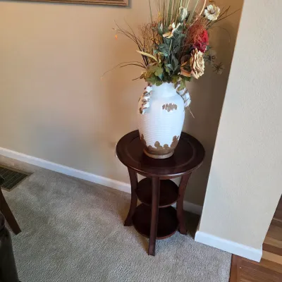 Sale Photo Thumbnail #75: Round dark wood three-tier accent table holding a textured white ceramic urn vase filled with faux botanical arrangements.