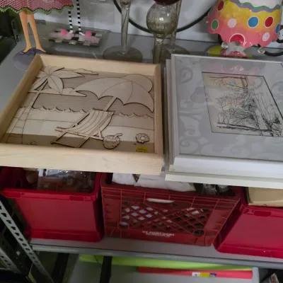Sale Photo Thumbnail #60: Unfinished wooden 3D beach scene shadow box alongside a framed landscape print, resting above red plastic crates.