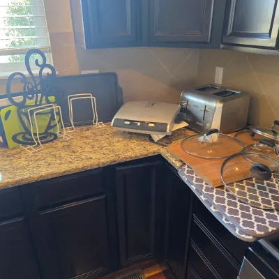 Sale Photo Thumbnail #115: Selection of kitchen small appliances and accessories, including a DeLonghi stainless steel toaster, a George Foreman grill, cookware glass lids, and a decorative coffee metal sign.